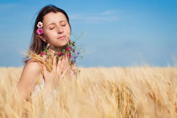 Kvinna med vilda blommor i fältet vete i sommar. — Stockfoto