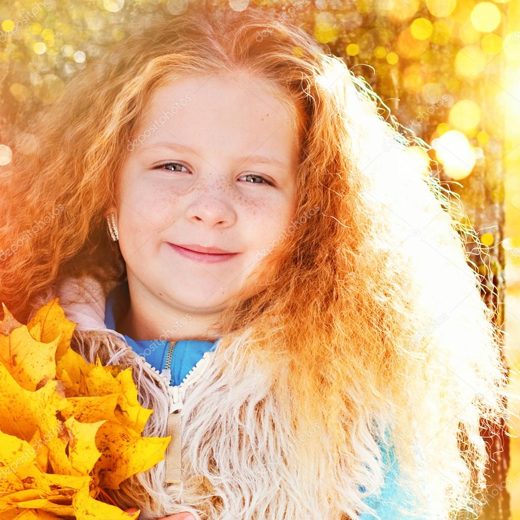 Beautiful Girl with Red Curly Hair in the Autumn Park