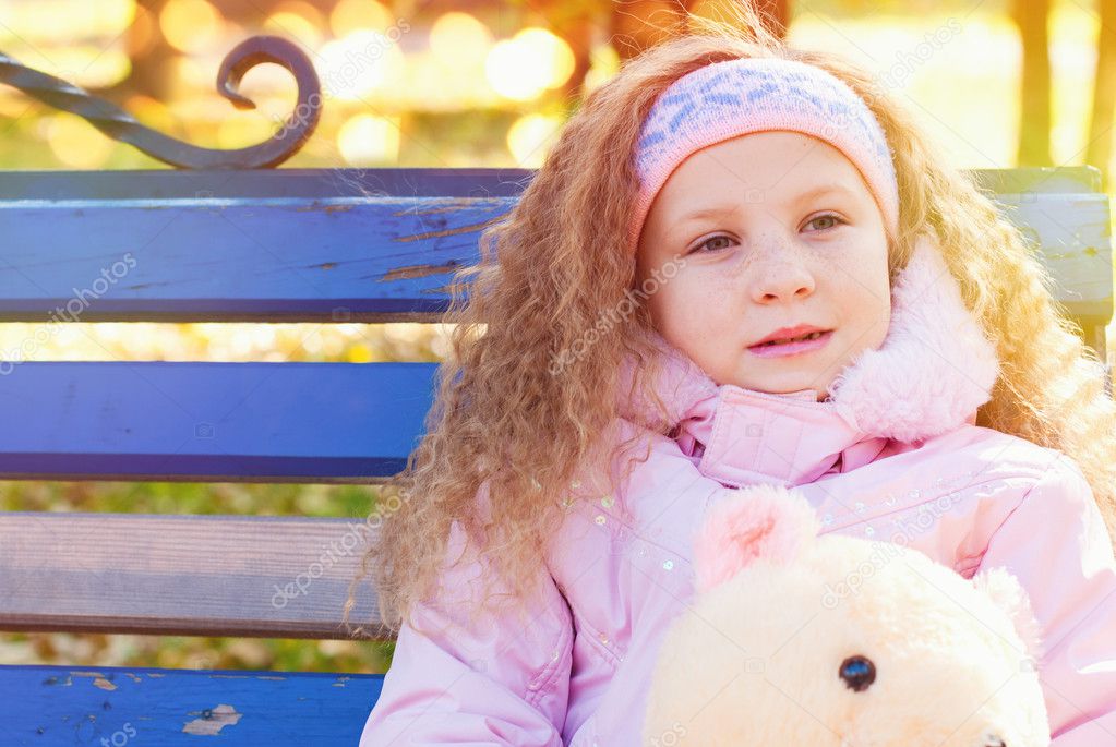 Beautiful Girl with Red Curly Hair in the Autumn Park