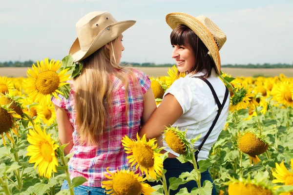 Schöne Mädchen mit Cowboyhüten auf dem Sonnenblumenfeld. — Stockfoto