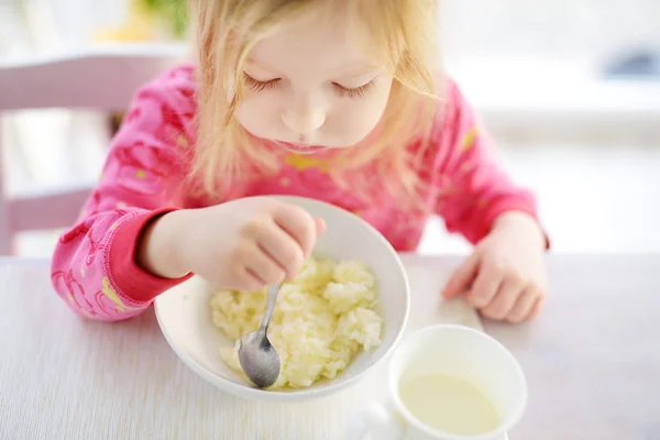 Söt liten flicka med havregrynsgröt till frukost — Stockfoto