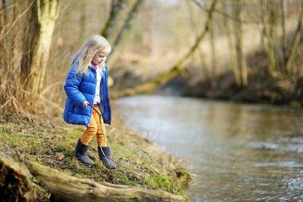 Dívka si hraje s holí u řeky — Stock fotografie
