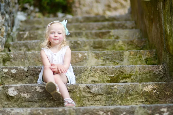 Очаровательная маленькая девочка сидит на лестнице — стоковое фото