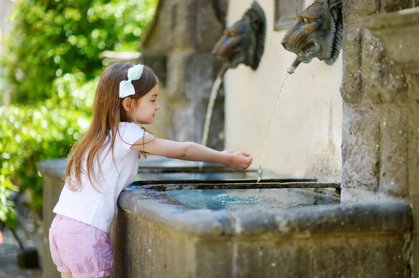 Klein meisje spelen met fontein — Stockfoto