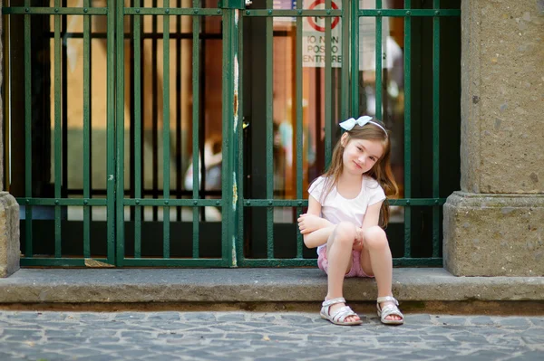 Kleines Mädchen sitzt vor der Haustür — Stockfoto