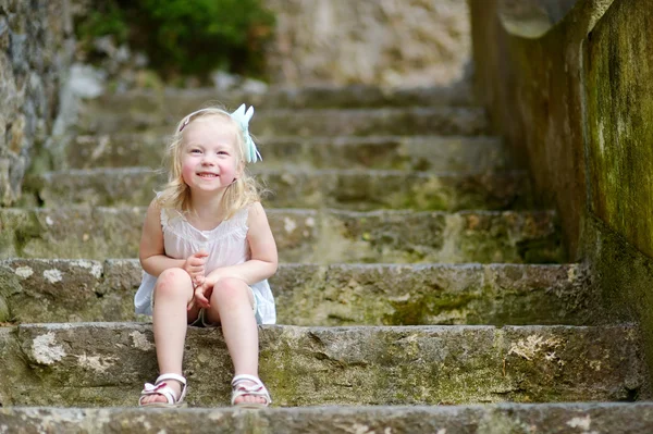 Rozkošná holčička sedí na schodech — Stock fotografie