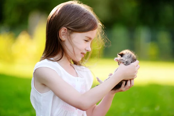 Маленькая девочка играет с маленьким котенком — стоковое фото