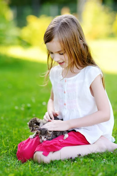 Маленькая девочка играет с маленькими котятами — стоковое фото