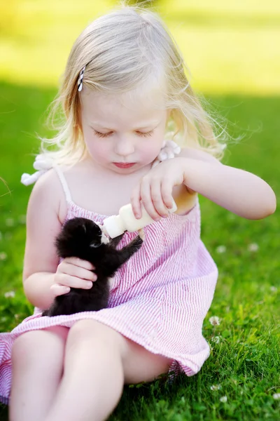 Menina alimentando pequeno gatinho — Fotografia de Stock