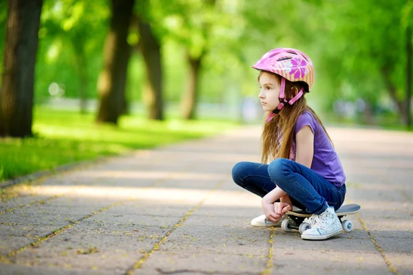 Meisje, zittend op een skateboard — Stockfoto
