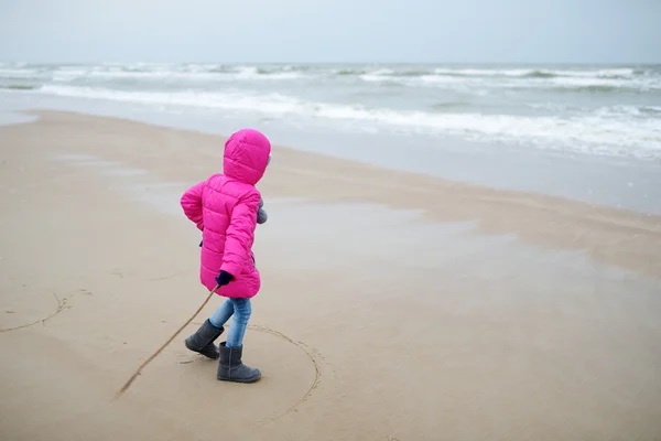 Маленькая девочка играет на берегу океана — стоковое фото