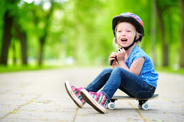 Μικρό κορίτσι που κάθεται σε ένα skateboard — 图库照片