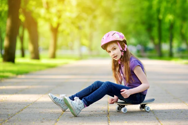 Bir kaykay üzerinde oturan küçük kız — Stok fotoğraf