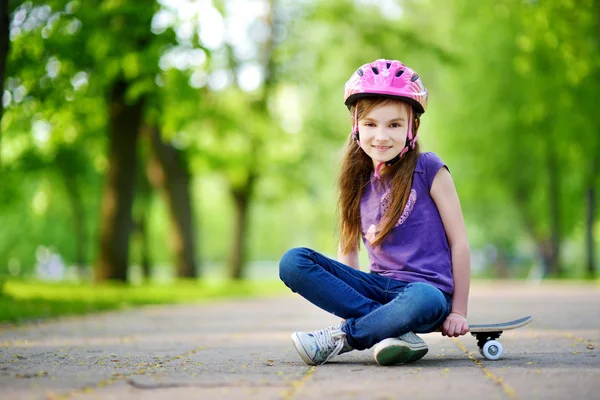 Μικρό κορίτσι που κάθεται σε ένα skateboard — 图库照片