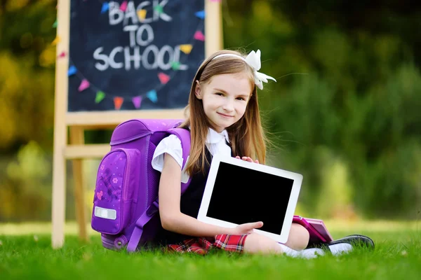 Liten skolflicka anläggning digital tablet — Stockfoto