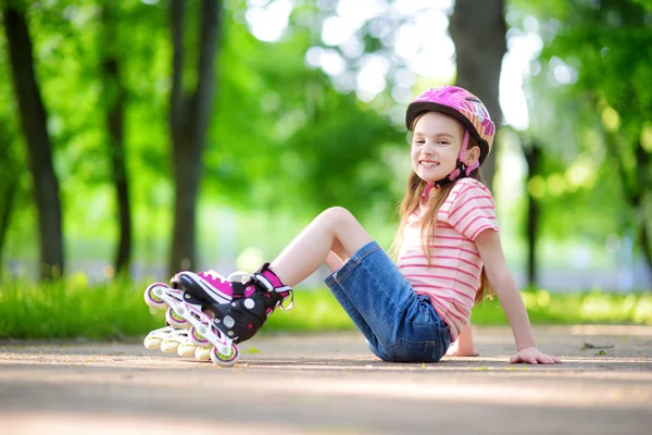 Küçük kız paten kaymayı öğreniyor. 