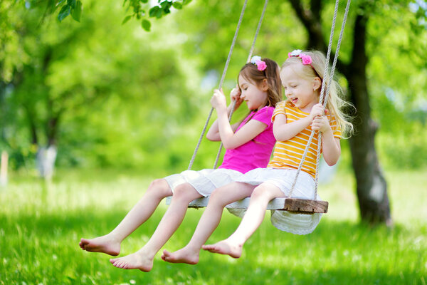Little sisters having fun on a swing