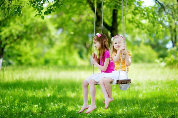 Little sisters having fun on a swing — Stock Photo, Image