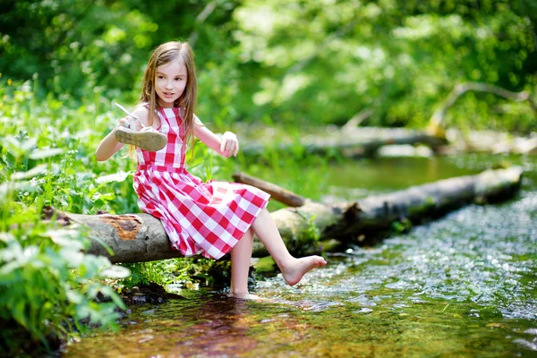 Malá dívka sedící na kládu u řeky — Stock fotografie