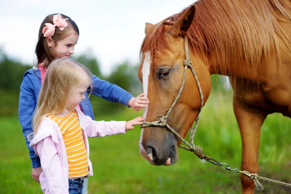 Sisters petting horse at countryside — Stock Photo, Image