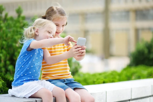 Hermanitas jugando con smartphone —  Fotos de Stock