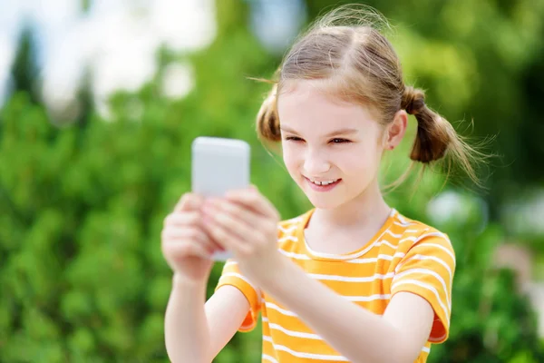 Flicka som leker utomhus mobilspel — Stockfoto