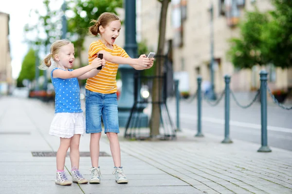 Sisters playing outdoor mobile game — Stock Photo, Image