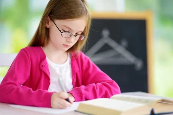Slimme kleine schoolmeisje schrijven test — Stockfoto