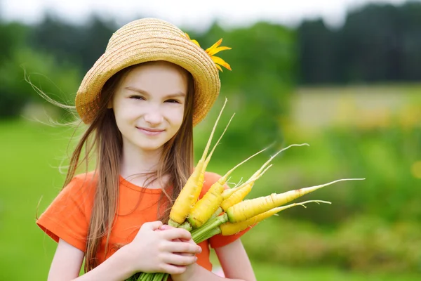 Ragazza carina che tiene carote gialle — Foto Stock