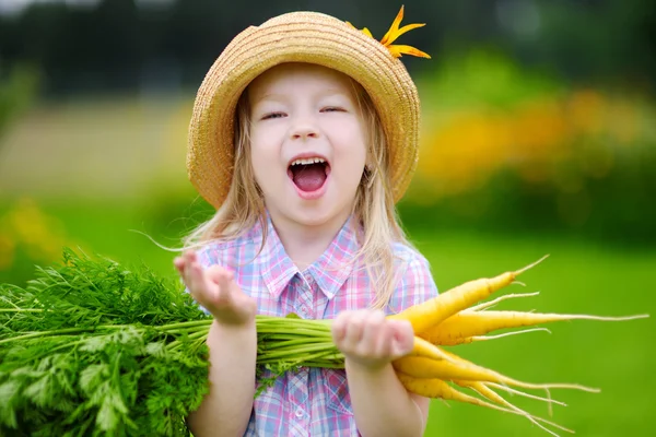 Cute girl holding yellow carrots — Stock Photo, Image
