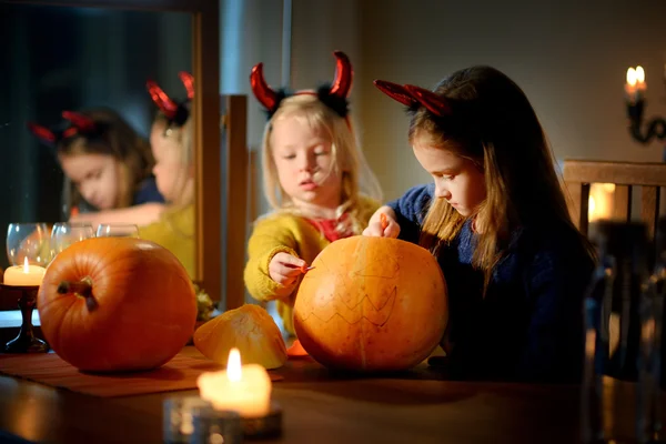 Pretty sisters carving pumpkin on Halloween — Stock Photo, Image