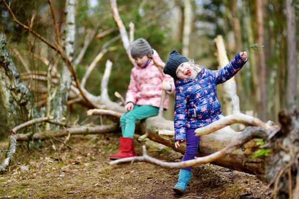 Lustige kleine Schwestern sitzen auf Baumstämmen — Stockfoto