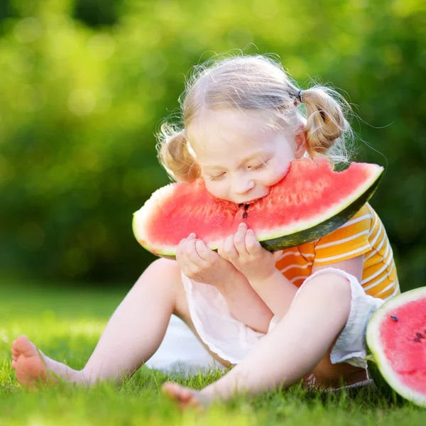 Lustiges kleines Mädchen beißt Wassermelone — Stockfoto