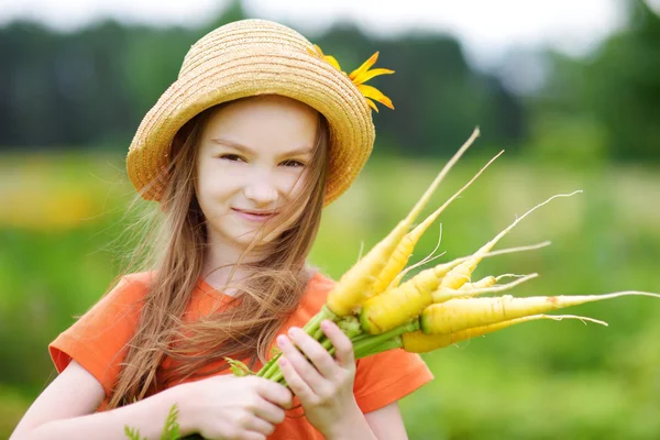 Cute girl holding yellow carrots — Stock Photo, Image