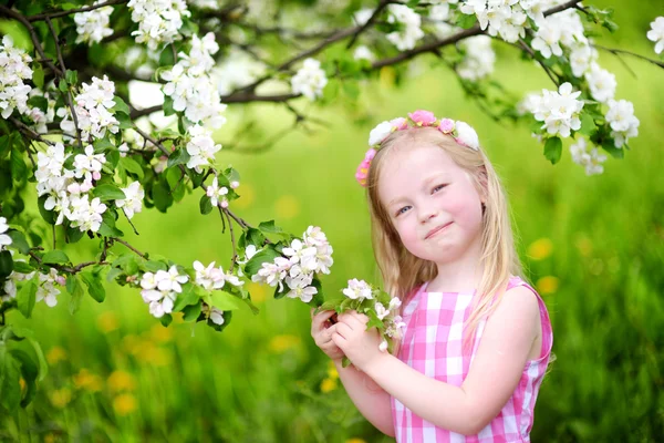 Klein meisje in de bloeiende appelboom — Stockfoto