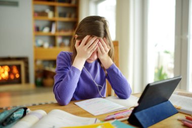 Liseli kız evde dijital tabletle ödevini yapıyor. Çocuk çalışmak için aletler kullanıyor. Çocuklar için eğitim ve uzak mesafe eğitimi. Karantina sırasında evde eğitim. Evde kalıp eğlenin..