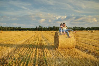 Sevimli genç kız kardeşler bir yaz günü buğday tarlasında eğleniyorlar. Hasat zamanı saman balyası tarlasında oynayan çocuklar. Çocuklar dışarıda günbatımının keyfini çıkarıyorlar. Litvanya 'da mahsul hasat etmek.