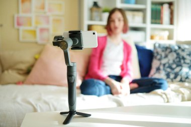 Güzel genç kız akıllı telefonuyla video blogu kaydediyor. Evde video blogu çeken genç bir vlogger. Genç nüfuzlu biri sosyal medya hesabı için içerik yaratıyor. Sosyal medya ve günlük tutma kavramı.