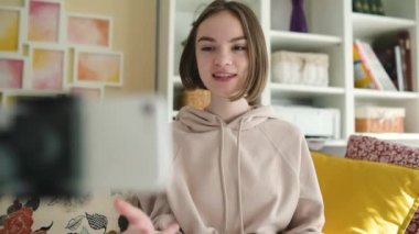 Güzel genç kız akıllı telefonuyla video blogu kaydediyor. Evde video blogu çeken genç bir vlogger. Genç nüfuzlu biri sosyal medya hesabı için içerik yaratıyor. Sosyal medya ve günlük tutma kavramı.