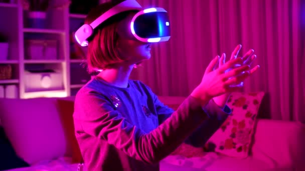 Ładna nastolatka dziewczyna w wirtualnej rzeczywistości zestaw słuchawkowy w ciemnym pokoju — Wideo stockowe