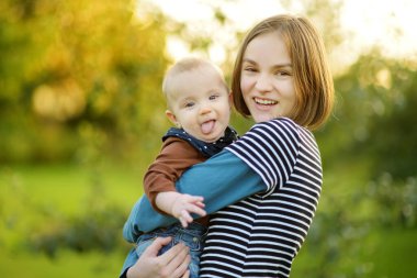 Küçük erkek kardeşine hayran sevimli bir abla. Sevimli genç kız yeni erkek kardeşini kucağında tutuyor. Geniş yaş farkı olan çocuklar. Kardeşler arasında büyük yaş farkı var. Büyük aile..