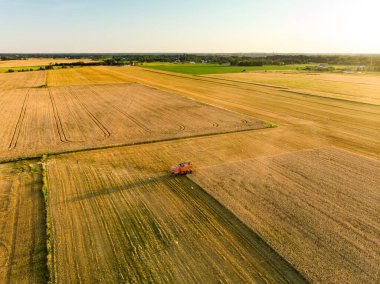 Farklı ekinlerden oluşan tarımsal parsellerin havadan görünüşü. Saman balyası tarlaları ve Litvanya 'nın tarım arazileri. Makine ya da ekipman topluyorum. Güneşli yaz akşamı.