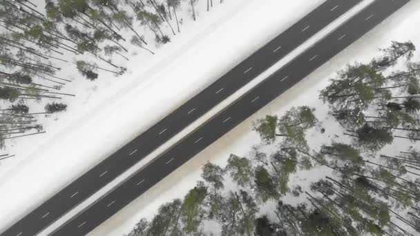 Felülről lefelé légi forgó kilátás havas erdő egy kétsávos út — Stock videók