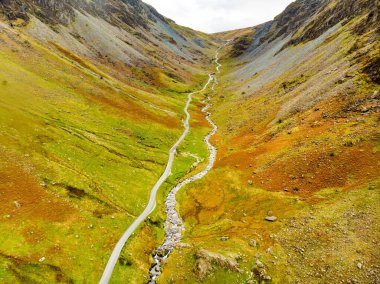 Aerial view of Honister Pass, a mountain pass with a road winding along Gatesgarthdale Beck mountain stream. One of the steepest and highest passes in the region. Cumbria, the Lake District, England. clipart