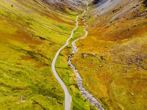 Aerial view of Honister Pass, a mountain pass with a road winding along Gatesgarthdale Beck mountain stream. One of the steepest and highest passes in the region. Cumbria, the Lake District, England.