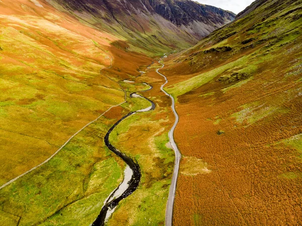 Aerial view of Honister Pass, a mountain pass with a road winding along Gatesgarthdale Beck mountain stream. One of the steepest and highest passes in the region. Cumbria, the Lake District, England.