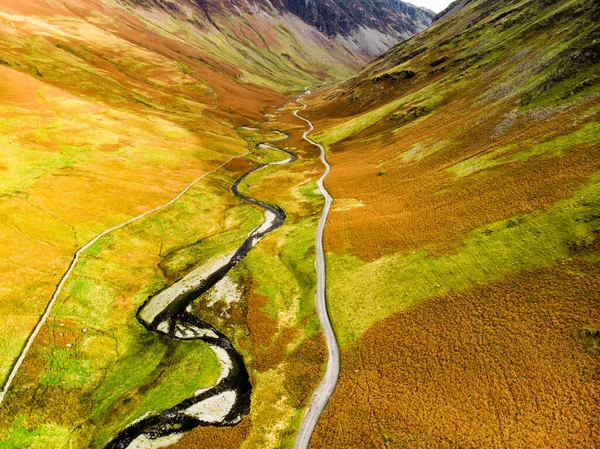 Aerial view of Honister Pass, a mountain pass with a road winding along Gatesgarthdale Beck mountain stream. One of the steepest and highest passes in the region. Cumbria, the Lake District, England.