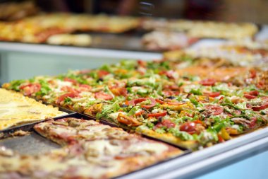 İtalya 'nın Bergamo şehrindeki küçük İtalyan pizzacısının tezgahında sergilenen kare pizza parçaları..