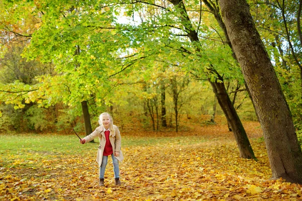 可爱的小女孩在美丽的秋日里玩得很开心 快乐的孩子在秋天的公园里玩耍 收集黄色落叶的孩子 为儿童开展的秋季活动 — 图库照片