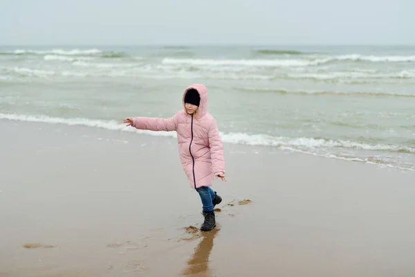 在寒冷的冬日 可爱的小女孩在冬季海滩上玩得很开心 孩子们在海边玩耍 儿童冬季活动 — 图库照片